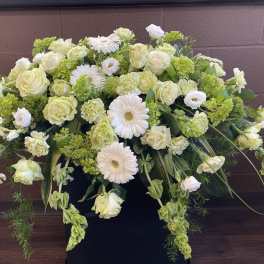 Large white and pale green floral arrangement in a black container