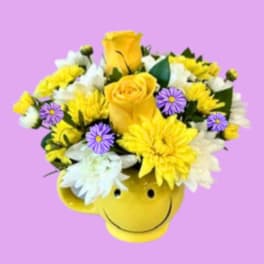 Yellow and white flower arrangement in a smiley-face mug
