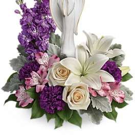 Purple and white floral arrangement with an angel figurine centerpiece