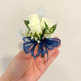 White rose boutonniere with blue ribbon and silver accents