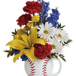 Mixed bouquet in a baseball mug with red, yellow, blue, and white flowers