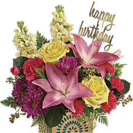 Mixed bouquet with pink lilies, yellow roses, and purple flowers in a gold vase