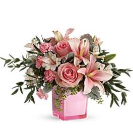 Pink roses and lilies arranged in a pink glass vase