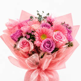 Pink and purple bouquet of roses and gerbera daisies wrapped in pink paper