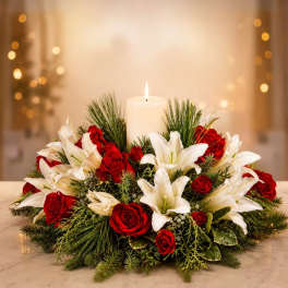 Red roses and white lilies arranged around a lit candle