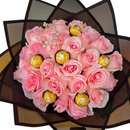 Pink rose bouquet with gold-wrapped chocolates in dark paper
