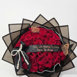 Bouquet of red roses wrapped in black paper with a ribbon and pearl accents