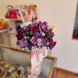 Purple and pink mixed bouquet in a white cup with a pink ribbon
