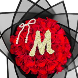 Round bouquet of red roses with a pearl bow and floral letter M