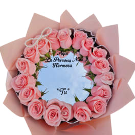 Pink rose bouquet arranged in a circular frame with a pearl bow