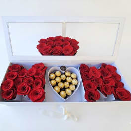Red roses arranged in a white gift box with heart-shaped chocolate candies