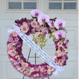 Heart-shaped floral wreath with pink roses and orchids on an easel