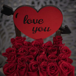 Red roses in a wooden basket with a heart-shaped "love you" sign