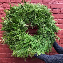 Green foliage wreath held against a red brick wall