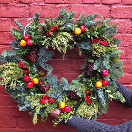 Holiday wreath with evergreen branches, berries, and small fruit accents