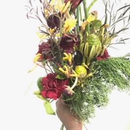Tall tropical bouquet with red and yellow flowers in a hand