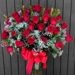Bouquet of red roses with baby's breath in a glass vase and red ribbon