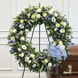 Large floral wreath with white and blue flowers on a stand