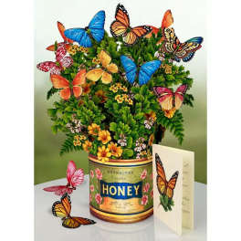 Butterflies arranged in a honey tin with small yellow flowers and a greeting card.