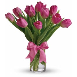 Pink tulip bouquet in a clear glass vase with a pink ribbon