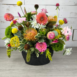 Colorful mixed flower arrangement in a black container