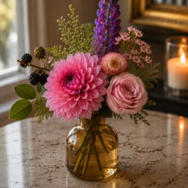 Pink and purple mixed bouquet in an amber glass vase
