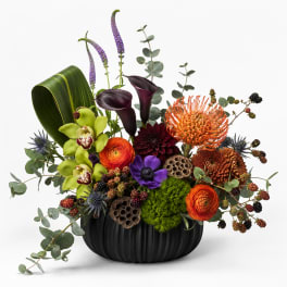 Mixed floral arrangement in a black vase with orange, purple, and green blooms