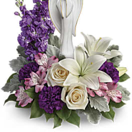 White angel figurine surrounded by purple and white flowers