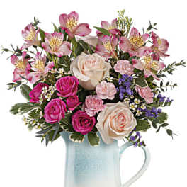 Pink and cream mixed flower bouquet in a blue ceramic pitcher