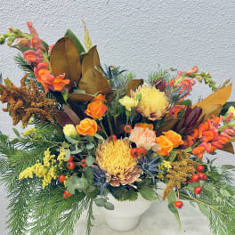 Autumn floral arrangement in a white vase with orange and yellow blooms