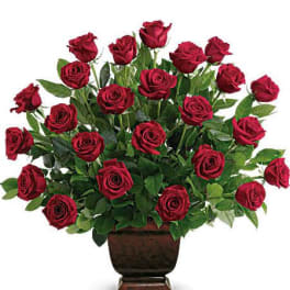 Tall arrangement of red roses in a dark pedestal vase