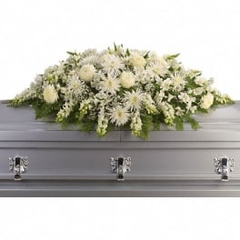 Long white casket spray with chrysanthemums and other flowers on a silver casket