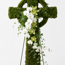 Moss-covered standing cross with white and green orchids