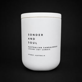 White scented candle in a lidded jar with black text