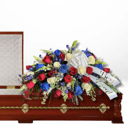 Red, white, and blue rose arrangement on a casket with a white bow