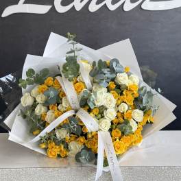 Bouquet of yellow and white roses with eucalyptus in white wrap