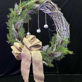 Rustic wreath with greenery, pinecones, and a burlap bow on a stand