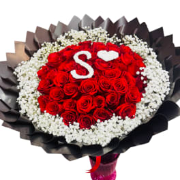 Round bouquet of red roses with white baby's breath and black wrapping