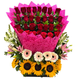 Bouquet of red roses with pink wrapping and sunflowers at the base
