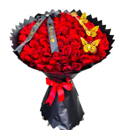 Large bouquet of red roses wrapped in black paper with a red ribbon