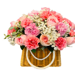 Pink and peach flower arrangement in a wicker basket