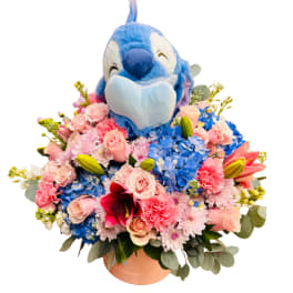 Blue plush bird sitting in a pink flower arrangement