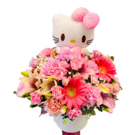 Pink flower arrangement with a Hello Kitty plush topper in a white container