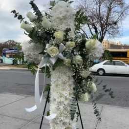 Tall white floral standing spray on an easel with ribbon
