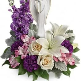 Purple and white floral arrangement with an angel figurine centerpiece