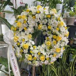 Heart-shaped floral wreath with yellow roses and white daisies on a stand