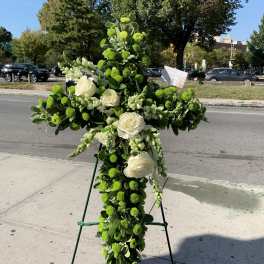 Large cross-shaped floral tribute with white roses and green pompons