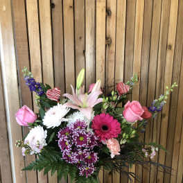 Mixed bouquet in a glass vase with pink roses, lilies, and purple blooms