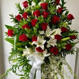 Standing spray of red roses and white lilies with a white ribbon