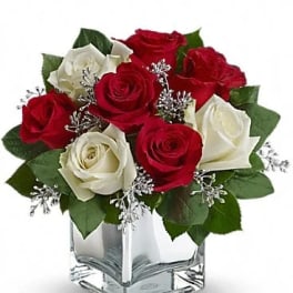 Red and white roses arranged in a clear square vase